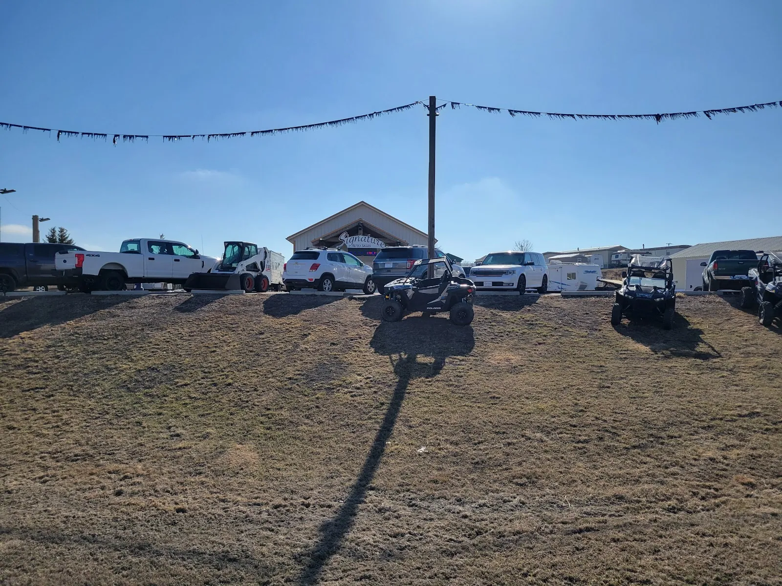 Rows of pickups and cars parked across the gravel lot under an open Dakota sky.